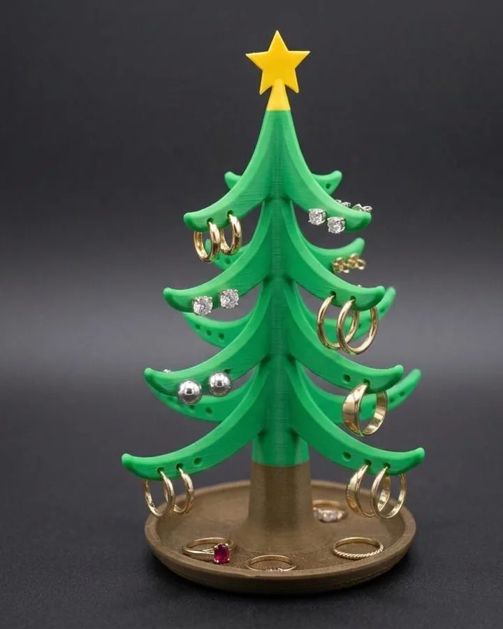 A green tiered tree with a brown trunk and gold star, earrings in the branch slots and a ring at the top.