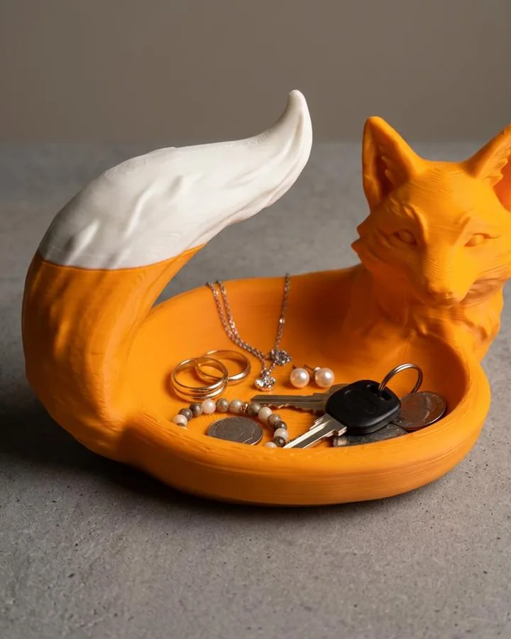 An orange fox-shaped dish with a white-tipped tail curling up behind a shallow oval bowl.
