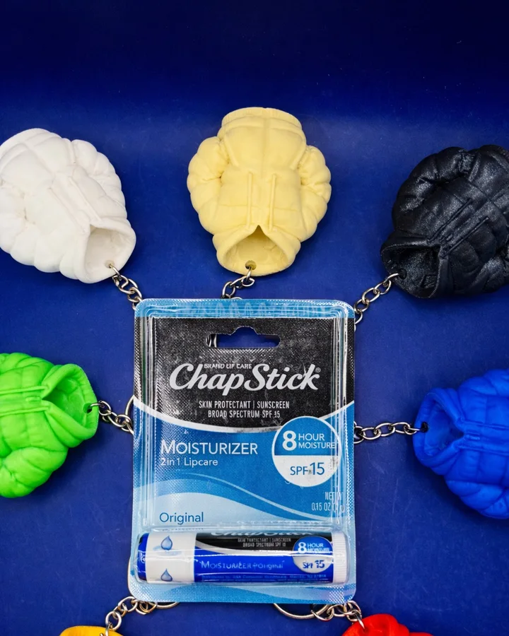 Two cream puffer jacket keychains that open to hold a lip balm